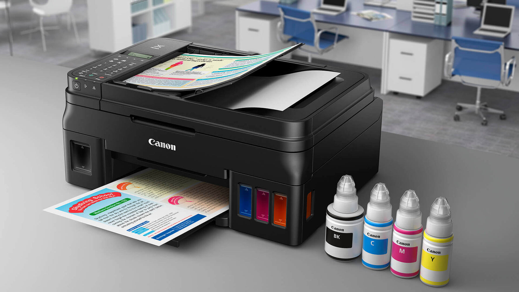 Canon printer with ink bottles on a desk in an office setting